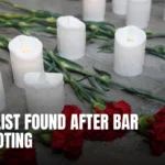Arrangement of red carnations and white candles on a stone surface, symbolizing peace and remembrance.